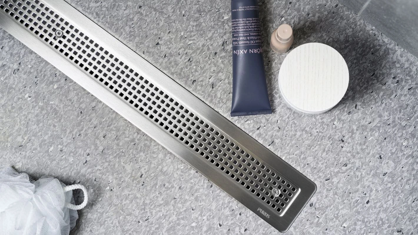 Wet room drain mechanically clamped into non-slip sheet vinyl flooring
