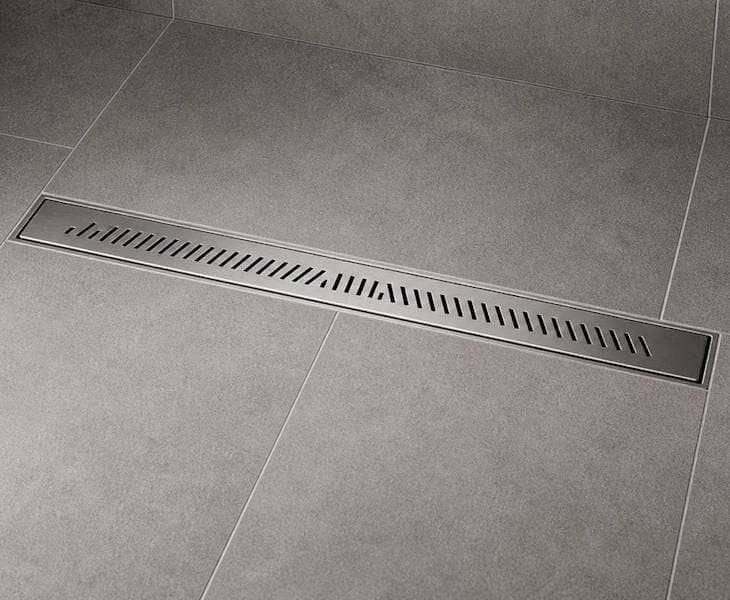 Linear drain with a visible stainless steel grid in a tiled wetroom floor